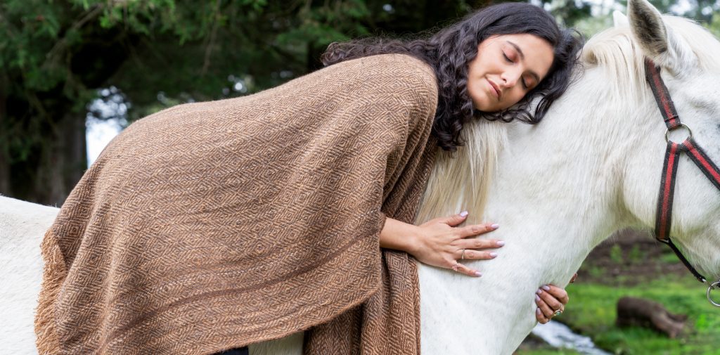 Mujer vistiendo paqocha alcapac ecuador recostada sobre el lomo de un caballo